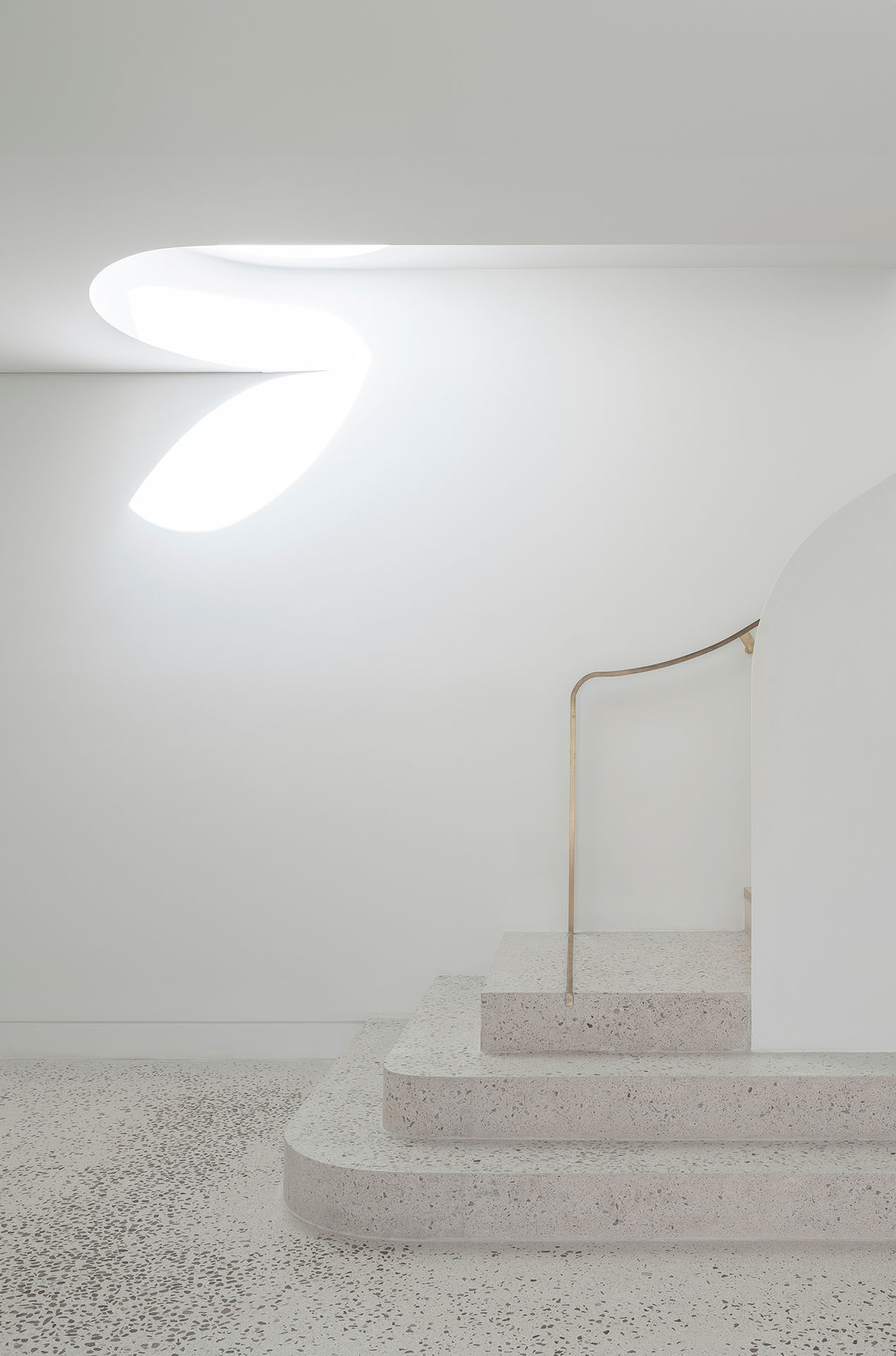 Minimal white interior with terrazzo steps and brass handrail